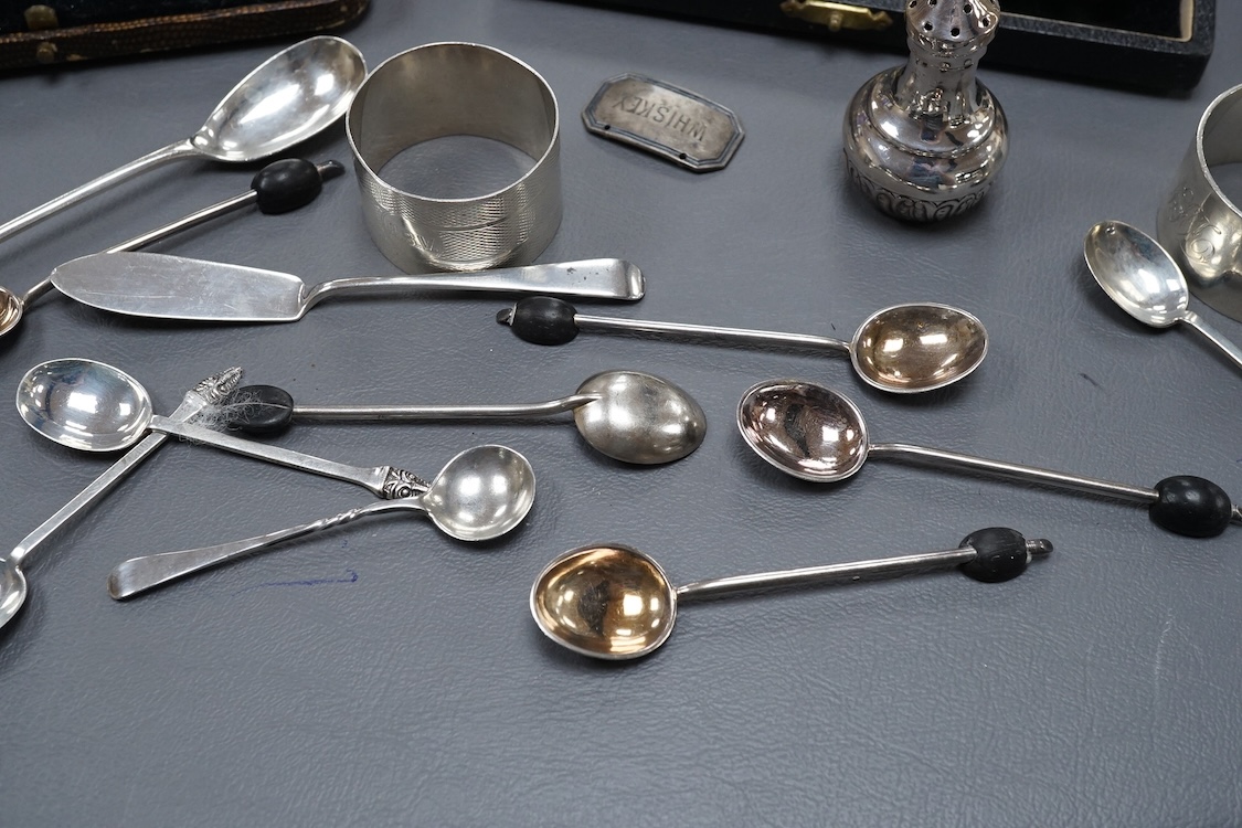 Four assorted silver napkin rings, two cased sets of six silver spoons, four silver condiments including a pair, a small group of sundry flatware, a silver wine label and a plated napkin ring.